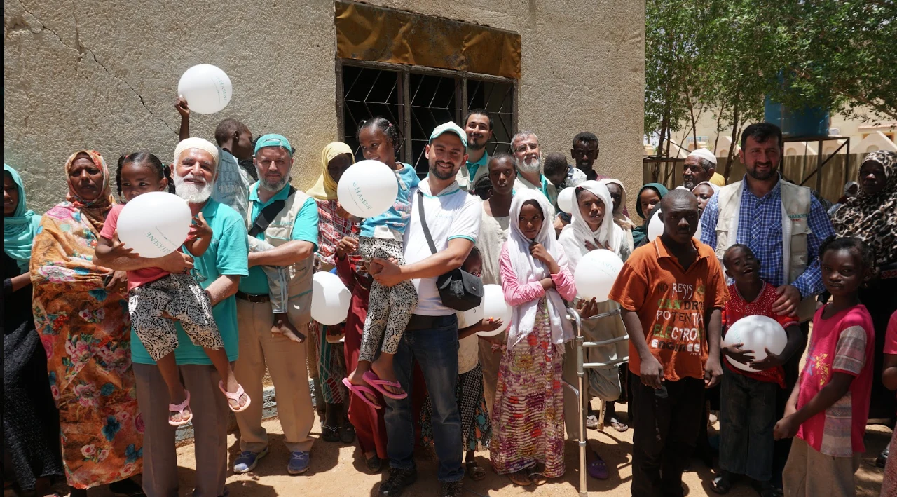 A group photo with volunteers and community members holding balloons in Sudan